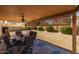 Covered patio with dining set and privacy screens, overlooking the gravel backyard at 8952 W Monte Vista Rd, Phoenix, AZ 85037