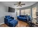 Comfortable living room with wood flooring, a ceiling fan, a mounted TV, and plush blue couches at 8952 W Monte Vista Rd, Phoenix, AZ 85037