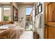 Bathroom with travertine floors, natural wood door, and a view to a private courtyard at 10531 E Cinder Cone Trl, Scottsdale, AZ 85262