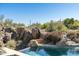 Swimming pool with waterfall feature is surrounded by desert landscaping and mature vegetation at 10531 E Cinder Cone Trl, Scottsdale, AZ 85262