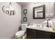 Cozy powder room features a dark vanity, white toilet, decorative mirrors, and lavender walls at 10566 E Bogart Ave, Mesa, AZ 85208