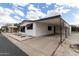 Exterior featuring a carport, white siding and stone landscaping, on a sunny day at 11000 N 91St Ave # 101, Peoria, AZ 85345