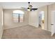 Neutral bedroom has a large window, ceiling fan, carpet and door to an adjoining room at 13620 N 82Nd Ln, Peoria, AZ 85381