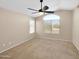 Well-lit bedroom features large window, ceiling fan, neutral walls, and plush carpeting at 13620 N 82Nd Ln, Peoria, AZ 85381