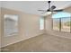 Bright bedroom featuring a ceiling fan and large windows with neutral walls and carpeting at 13620 N 82Nd Ln, Peoria, AZ 85381