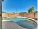 A backyard pool features a charming waterfall feature and desert landscaping for a relaxing outdoor space at 13620 N 82Nd Ln, Peoria, AZ 85381