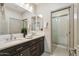 Elegant bathroom featuring double sinks, dark wood cabinets, and a glass shower at 15711 S 11Th Ave, Phoenix, AZ 85045
