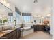 This elegant bathroom has dual sinks, dark wood cabinets, a large soaking tub, and picture windows at 15711 S 11Th Ave, Phoenix, AZ 85045