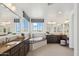 Bright bathroom with dual vanities, soaking tub, and large window with neighborhood views at 15711 S 11Th Ave, Phoenix, AZ 85045