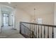 Upstairs hallway featuring neutral carpet, arches, and a decorative chandelier at 15711 S 11Th Ave, Phoenix, AZ 85045