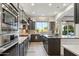 Modern kitchen featuring stainless steel appliances, dark cabinetry, island, and a window overlooking lush greenery at 15711 S 11Th Ave, Phoenix, AZ 85045