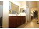 Well-lit bathroom with a double sink vanity, mirrored wall, tiled floors and access to bedroom at 17516 W Pershing St, Surprise, AZ 85388