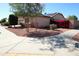 A cozy house exterior on the corner of a sidewalk has manicured landscaping and desert-style rock at 17516 W Pershing St, Surprise, AZ 85388