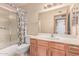 Cozy bathroom features shower with patterned curtain, wooden cabinets, and patterned wallpaper at 18814 N 33Rd Ave, Phoenix, AZ 85027
