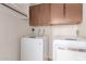 Bright laundry room featuring a modern washer and dryer set with storage cabinets above at 18814 N 33Rd Ave, Phoenix, AZ 85027