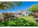 Expansive backyard features a lush lawn, desert landscaping, covered patio, and charming two-story home at 19829 N 97Th St, Scottsdale, AZ 85255