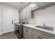 Laundry room features grey cabinets, stainless steel sink, washer and dryer and a door at 19829 N 97Th St, Scottsdale, AZ 85255