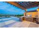 Stylish outdoor kitchen and bar area overlooking the pool with pergola and desert landscape at 19829 N 97Th St, Scottsdale, AZ 85255