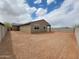 The exterior view of the home reveals the spacious, unfinished backyard with a block wall and ample space at 20795 N Roadrunner Ln, Maricopa, AZ 85138