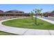 A view of the community park including walking paths and manicured landscaping with neighborhood homes in the background at 20795 N Roadrunner Ln, Maricopa, AZ 85138