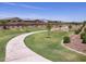 Manicured green space featuring a curved sidewalk, vibrant green grass, and small decorative trees at 20795 N Roadrunner Ln, Maricopa, AZ 85138