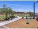Community playground featuring a black bench and unique play structure, surrounded by trees and green space at 20795 N Roadrunner Ln, Maricopa, AZ 85138