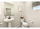 Charming powder room features a pedestal sink, elongated toilet, framed art, and natural light from the window at 22962 N 182Nd Ln, Surprise, AZ 85387