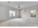 Spacious bedroom featuring neutral carpeting, ceiling fan, and bright natural light from two large windows at 29214 N 19Th Ln, Phoenix, AZ 85085