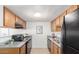 Full kitchen view with wood cabinets, granite countertops, black appliances and a stainless steel sink at 3511 E Baseline Rd # 1235, Phoenix, AZ 85042