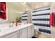 Well-lit bathroom featuring a dual sink vanity and a tub with striped shower curtain at 3914 S 58Th Ln, Phoenix, AZ 85043