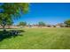 Community park featuring lush green grass, mature trees, picnic benches, and a playground in the distance at 4349 W Cielo Grande --, Glendale, AZ 85310