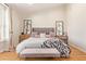 Bright main bedroom with wood floors features a tufted headboard and bench with decorative pillows and throws at 4419 N 24Th Way, Phoenix, AZ 85016
