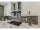Sleek kitchen showcasing quartz countertops, gray tile backsplash, stainless steel range hood, and modern cooktop at 4509 E La Puente Ave, Phoenix, AZ 85044