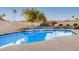 Community pool area with a jacuzzi, surrounded by desert landscaping and security fencing at 5445 E Mckellips Rd # 23, Mesa, AZ 85215