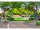 Neighborhood park with mature trees, grass, gravel walkway, and desert plants at 6112 E Jenan Dr, Scottsdale, AZ 85254