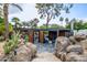 Stylish outdoor living space featuring a covered patio, lounge seating, stone flooring, and lush desert landscaping at 6112 E Jenan Dr, Scottsdale, AZ 85254