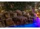 Water cascading down a custom rock waterfall into the stunningly lit swimming pool at 6112 E Jenan Dr, Scottsdale, AZ 85254
