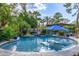 Outdoor pool area showcases lush landscaping, a rock waterfall, and in-pool seating with umbrella at 6112 E Jenan Dr, Scottsdale, AZ 85254