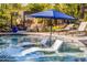 Outdoor pool area showcases lush landscaping, nearby pizza oven, and in-pool seating with umbrella at 6112 E Jenan Dr, Scottsdale, AZ 85254