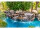 Close-up view of a waterfall cascading into the turquoise pool at 6112 E Jenan Dr, Scottsdale, AZ 85254