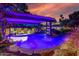 Twilight image shows lush landscaping and violet lighting around a gorgeous pool area at 6112 E Jenan Dr, Scottsdale, AZ 85254
