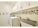 Well-organized laundry room with plenty of storage, a utility sink and modern appliances for convenience at 6350 S Four Peaks Pl, Chandler, AZ 85249