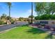 Elegant community entrance with mature landscaping, lush green grass, and a welcoming sign at 7575 E Indian Bend Rd # 1137, Scottsdale, AZ 85250
