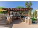 Outdoor kitchen and entertainment area with BBQ, pergola, and bar seating at 7608 W Mescal St, Peoria, AZ 85345