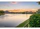 Scenic waterfront view with palm trees, mountain backdrop, and vibrant sunset colors at 8429 E Del Camino Dr, Scottsdale, AZ 85258