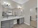 Bathroom featuring double vanity with grey cabinets, a large mirror, and a walk-in closet at 8854 W Augusta Ave, Glendale, AZ 85305
