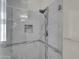 Contemporary glass-enclosed shower with marble tiling, niche, and modern fixtures at 8854 W Augusta Ave, Glendale, AZ 85305