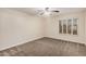 An empty room features neutral carpet, a ceiling fan, and a window with shutters at 917 N Blackbird Dr, Gilbert, AZ 85234