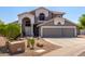 Two-story home with neutral gray exterior, desert landscaping, and three-car garage showcasing curb appeal and functionality at 9203 E Topeka Dr, Scottsdale, AZ 85255