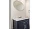 Bathroom vanity features an oval mirror, neutral countertop, and navy blue cabinets at 921 W University Dr # 1038, Mesa, AZ 85201